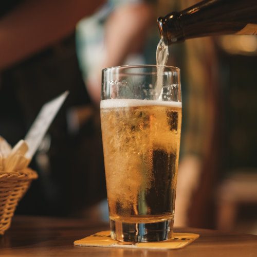 Ein Glas wird mit Bier aus einer Flasche gefüllt.